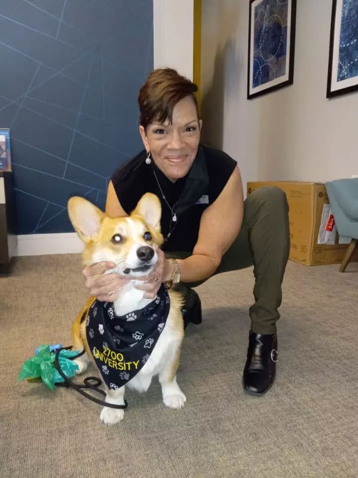 A woman kneeling down with her corgi dog