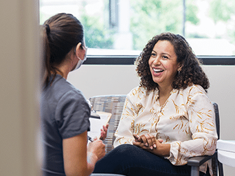 Two woman sitting across from each other smiling