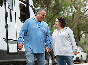 A man and woman holding hands outside of an RV